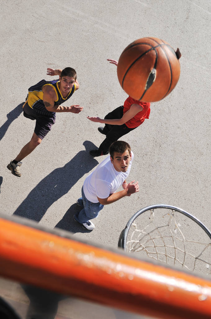 gorup mladých chlapců, kteří hrají basketbal venkovní na ulici s dlouhými stíny a pohled na ptáky perspektivu - Fotografie, Obrázek
