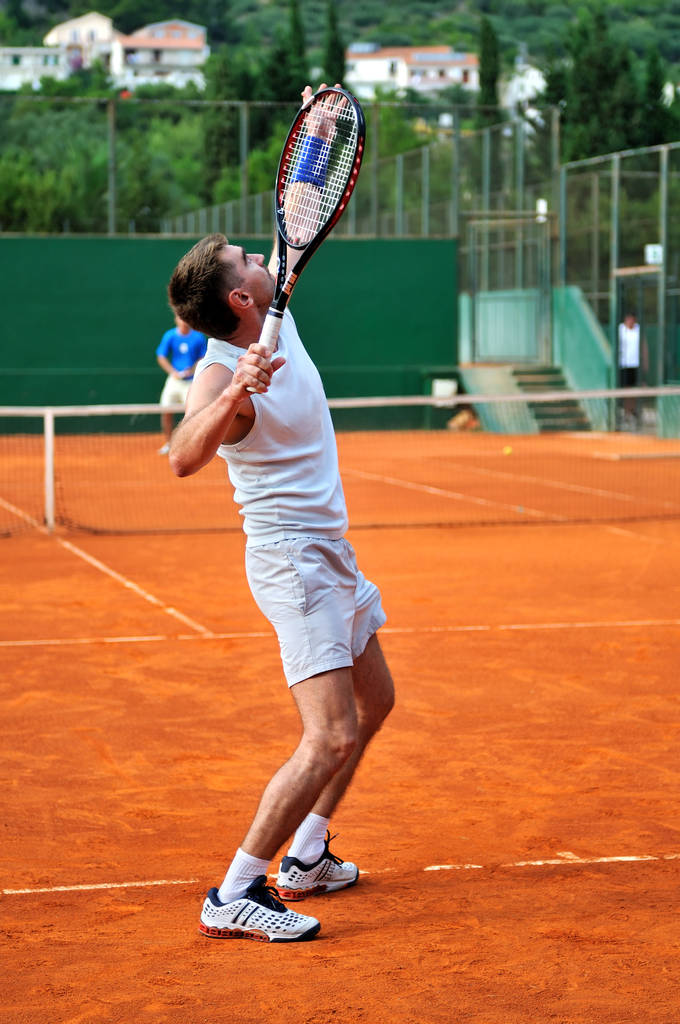 Один мужчина играет в теннис на открытом корте - Фото, изображение