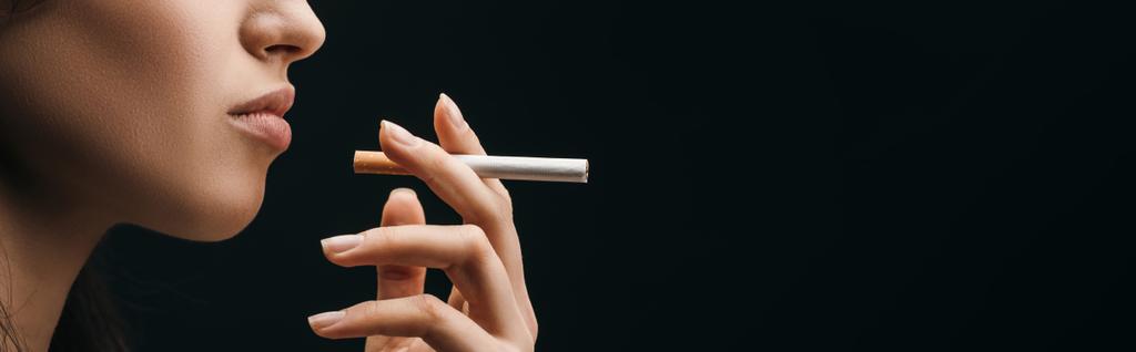 Πλευρική άποψη της γυναίκας κρατώντας τσιγάρο απομονώνονται σε μαύρο, πανοραμική βολή - Φωτογραφία, εικόνα
