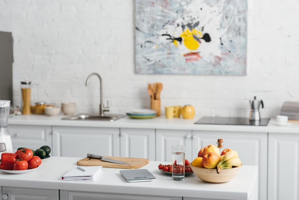 Свежие овощи, фрукты со стаканом воды и ноутбуком на кухонном столе, диета подсчета калорий
 - Фото, изображение