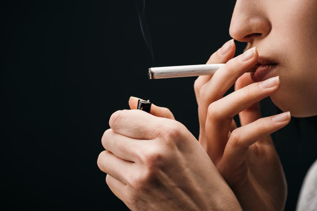 Sivunäkymä nuori nainen valaistus savuke kevyempi eristetty musta
  - Valokuva, kuva