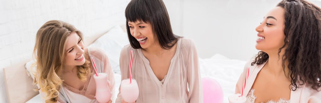 panoramiczne ujęcie wielokulturowych dziewczyn i śmiejącej się ciężarnej kobiety trzymającej okulary z koktajlami mlecznymi na baby shower  - Zdjęcie, obraz