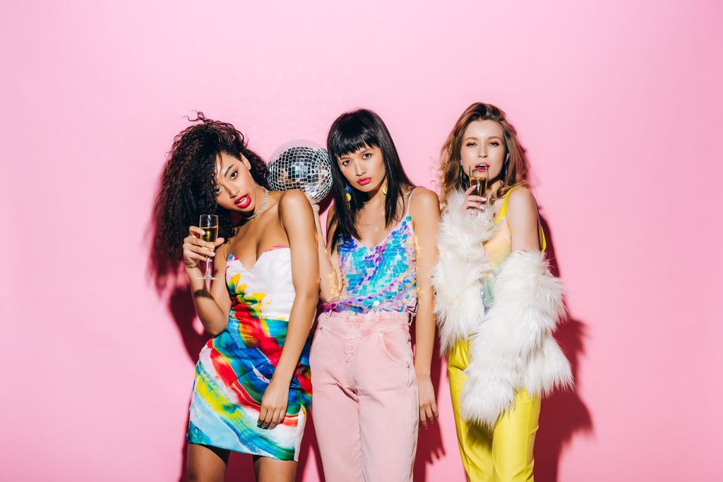 sexy multikulturelle Freundinnen mit Champagner und Discokugel posieren auf rosa - Foto, Bild