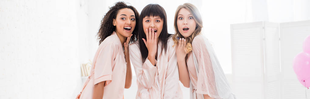 panoramic shot of shocked multicultural girls in bathrobes having bachelorette party - Photo, Image