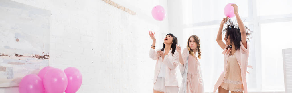 tiro panorâmico de meninas multiculturais alegres se divertindo com balões rosa na despedida de solteira
 - Foto, Imagem
