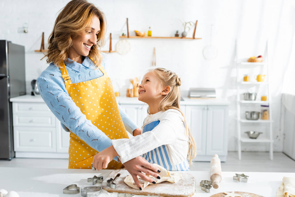 smiling mother and cute daughter cooking cookies in kitchen  - Photo, Image