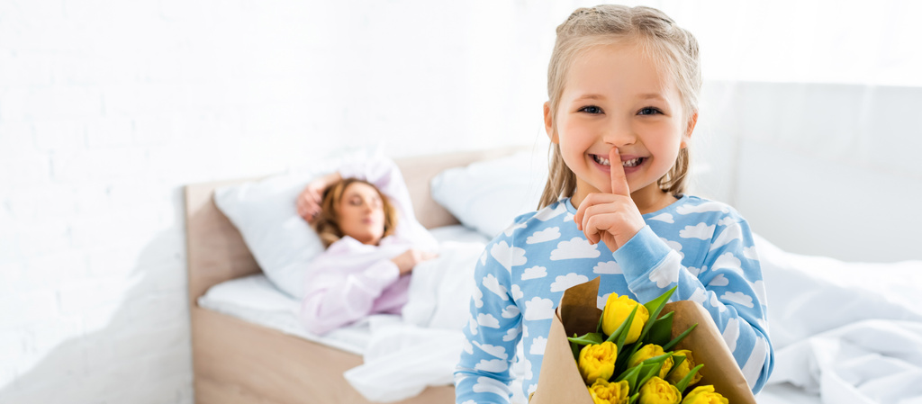 panoramic shot of smiling daughter showing shh and holding bouquet in mothers day - Photo, Image