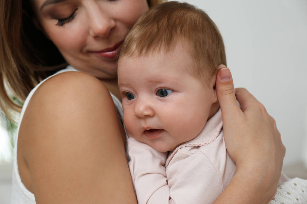 Jonge vrouw met haar kleine baby rusten na borstvoeding thuis, close-up - Foto, afbeelding