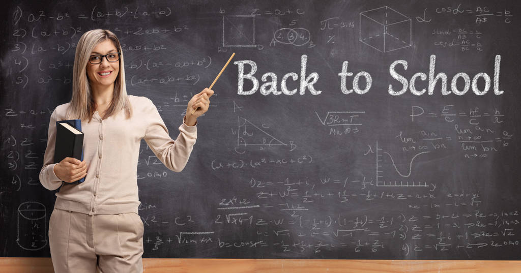 Female teacher pointing to a blackboard with text back to school - Photo, Image