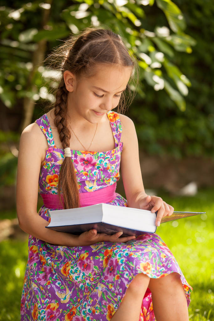 Muotokuva söpö brunette tyttö lukee iso kirja metsässä
 - Valokuva, kuva