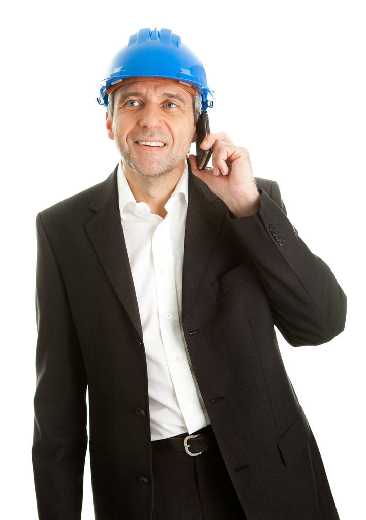 Portret van architect dragen blauwe harde hoed en praten op mobiele telefoon. geïsoleerd op wit - Foto, afbeelding