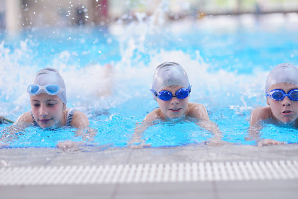 Yüzme havuzunda yüzmeyi öğrenen bir grup mutlu çocuk. - Fotoğraf, Görsel