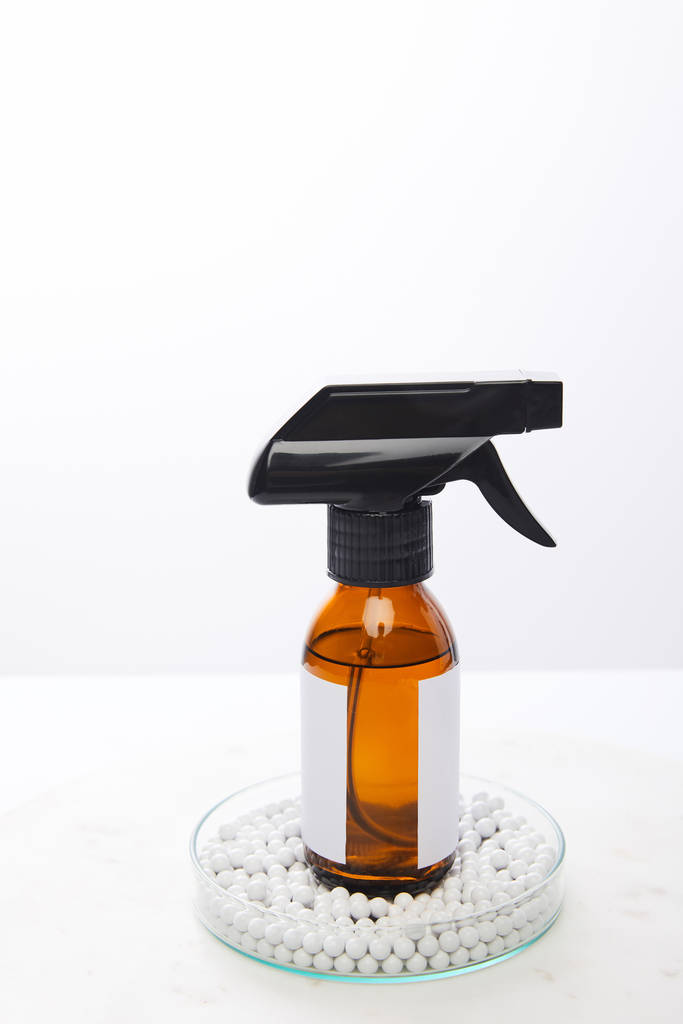Botella dispensadora de aceite cosmético dentro de cristalería de laboratorio con perlas decorativas aisladas en blanco
 - Foto, imagen