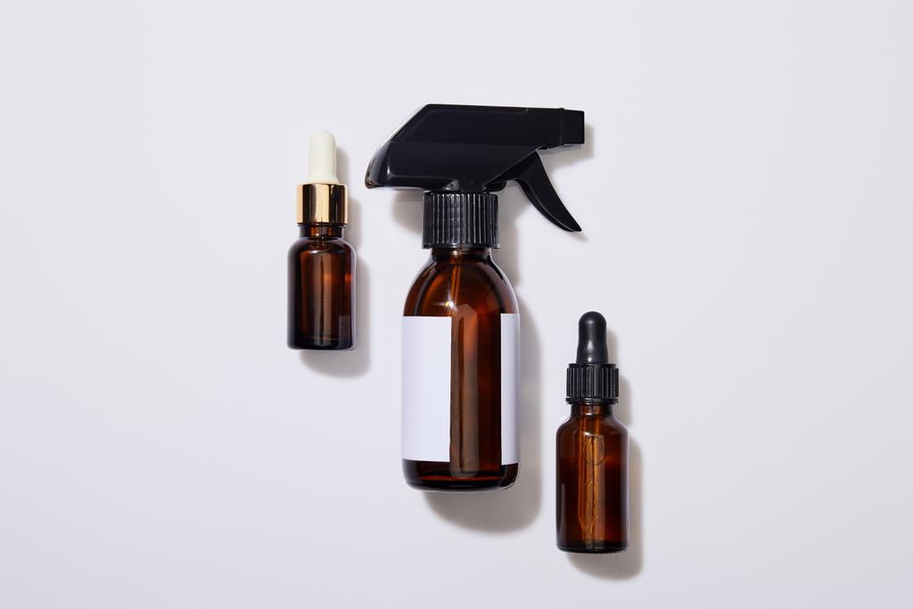 Draufsicht auf Spender Kosmetikflaschen mit Öl auf grauem Hintergrund - Foto, Bild
