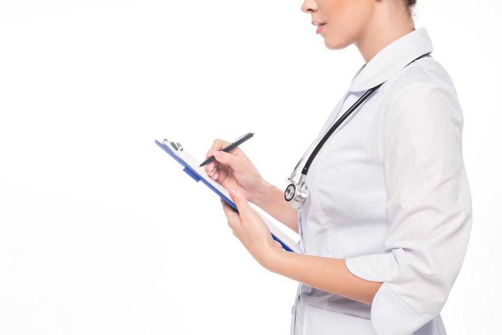 Cropped view of doctor with stethoscope writing on clipboard isolated on white - Photo, Image