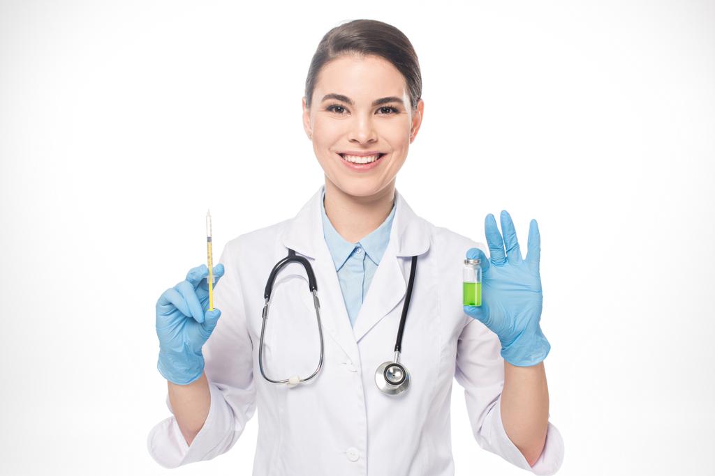 attraktive Ärztin lächelt in die Kamera, während sie Spritze und Impfstoff auf weiß isoliert hält - Foto, Bild