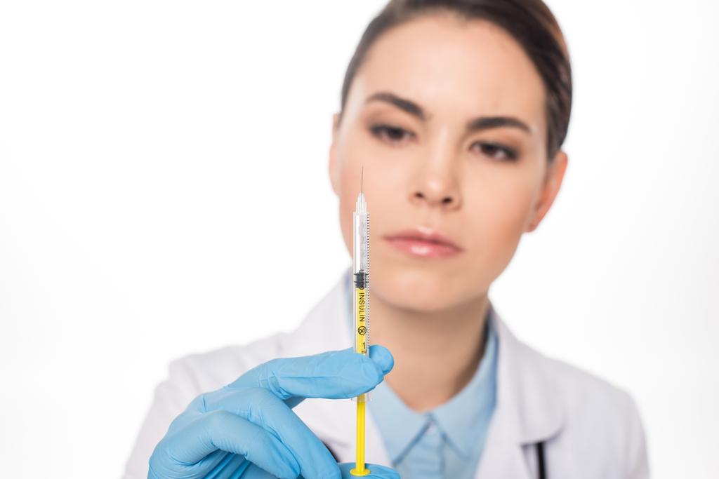 Enfoque selectivo de un médico atractivo que mira la jeringa con vacuna aislada en blanco
 - Foto, imagen