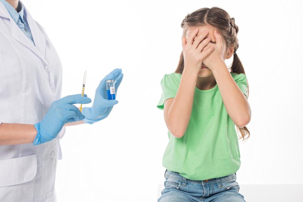Педиатр со шприцем и вакциной от гриппа рядом с испуганным ребенком, изолированным на белом
 - Фото, изображение