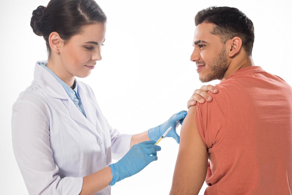 Patient souriant regardant un médecin faire une injection de vaccin isolé sur blanc
 - Photo, image