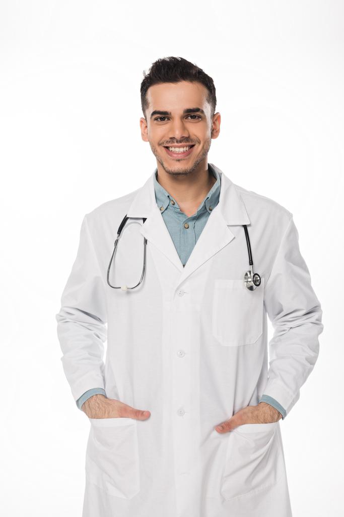 Usmívající se lékař se stetoskopem při pohledu na kameru izolované na bílém - Fotografie, Obrázek