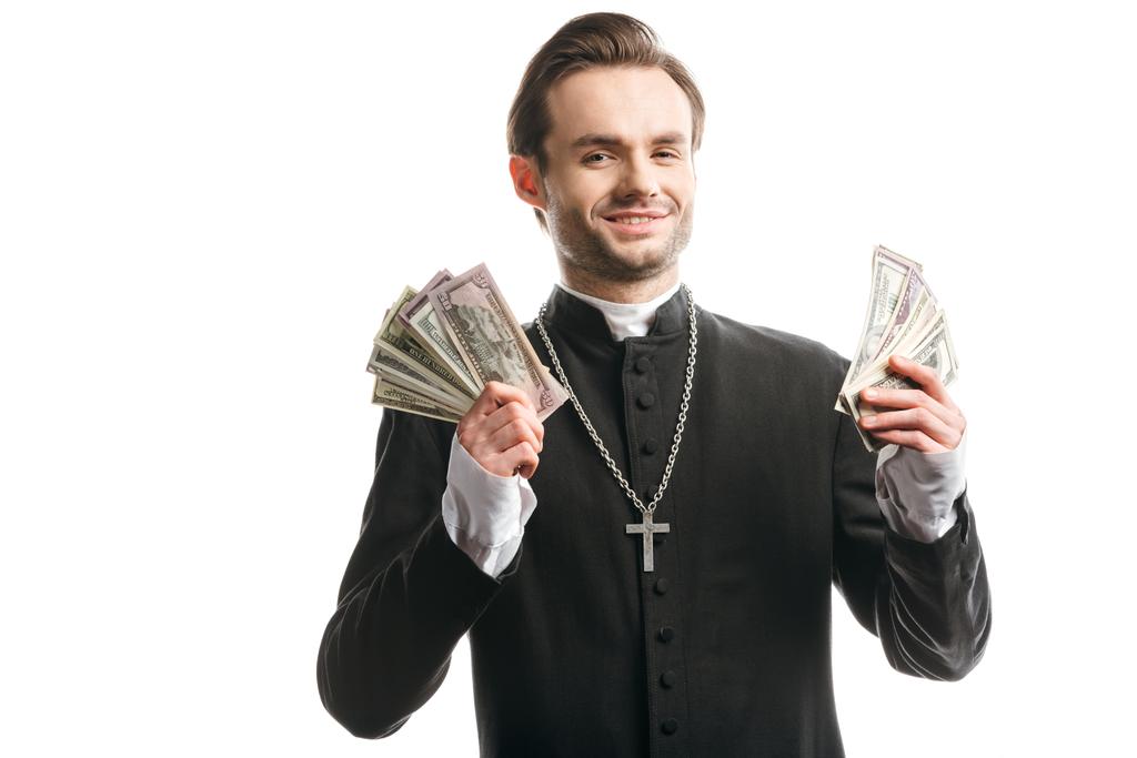 padre católico corrupto sorrindo para a câmera enquanto segurando notas de dólar isolado no branco
 - Foto, Imagem