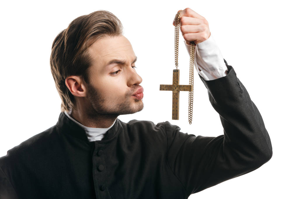 joven sacerdote católico insincero va a besar cruz de oro aislado en blanco
 - Foto, imagen