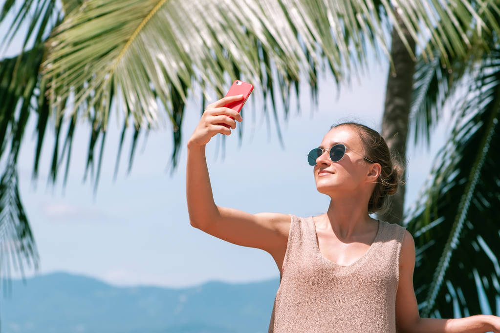 Jeune fille attrayante faisant selfie sur fond de palmiers de mer
 - Photo, image