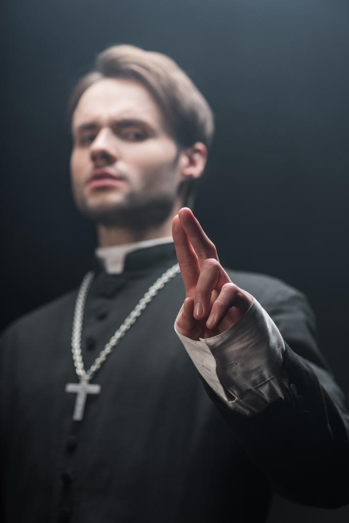 low angle view of confident catholic priest showing blessing gesture isolated on black - Photo, Image