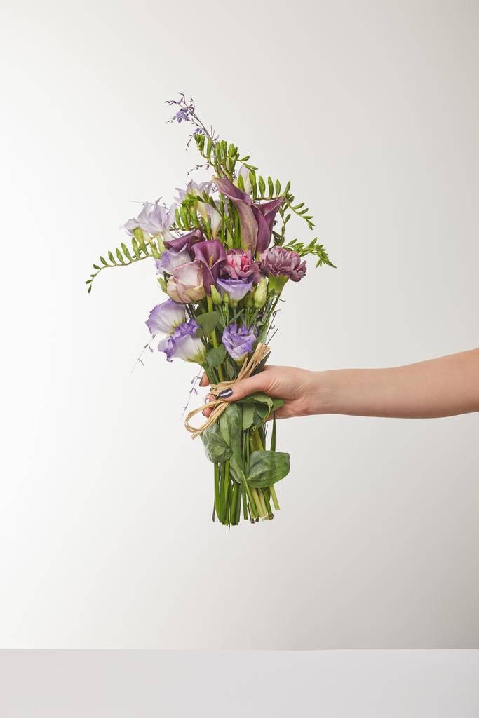 abgeschnittene Ansicht einer Frau mit einem Strauß violetter und lila Blumen auf weißem Grund - Foto, Bild