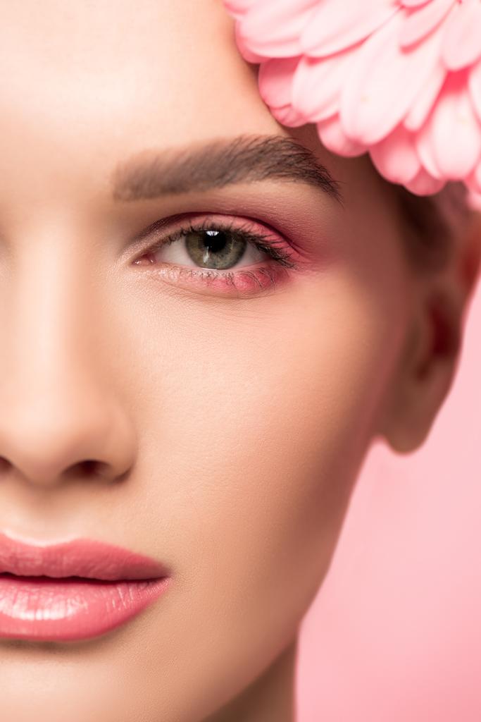 στενή άποψη του προσώπου του κοριτσιού με ροζ λουλούδι gerbera, απομονωμένο σε ροζ - Φωτογραφία, εικόνα