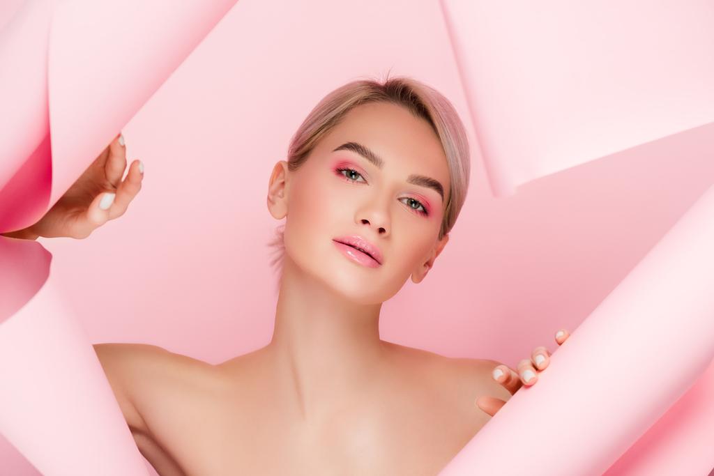 krásná nahá dívka s růžovým make-upem v roztrhaném papíru, izolované na růžové - Fotografie, Obrázek