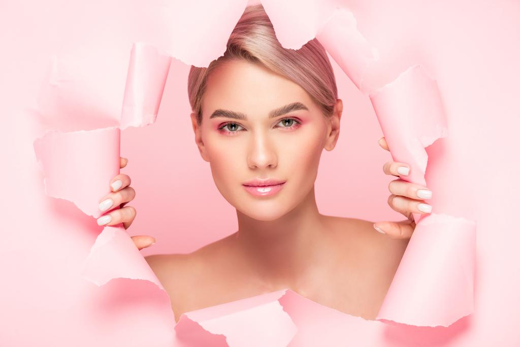piękne nagie dziewczyna z różowy makijaż w podarty papier, izolowane na różowy - Zdjęcie, obraz