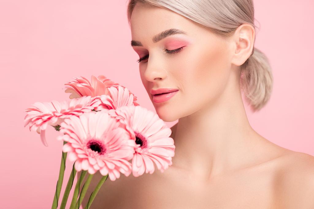 schönes Mädchen mit geschlossenen Augen und rosa Make-up mit Gerbera-Blüten, isoliert auf rosa - Foto, Bild