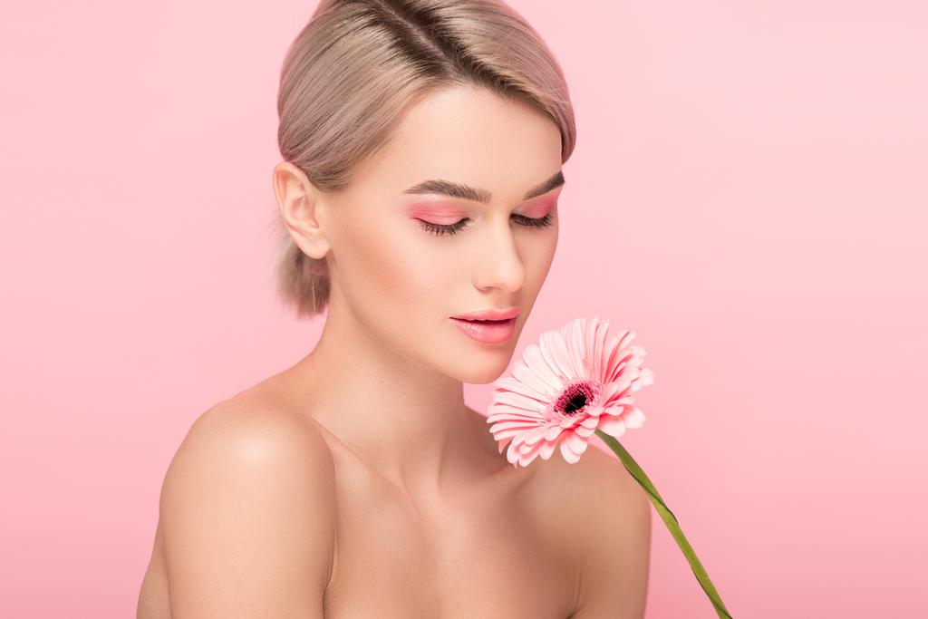 chica desnuda con los ojos cerrados sosteniendo flor de gerberas, aislado en rosa
 - Foto, Imagen