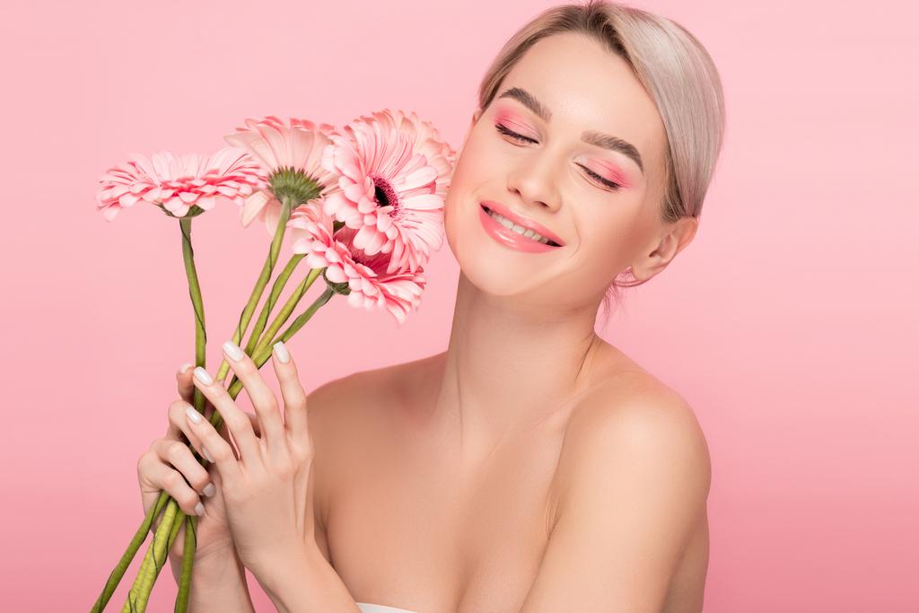 alegre chica desnuda con maquillaje rosa sosteniendo flores de gerberas, aislado en rosa
 - Foto, imagen