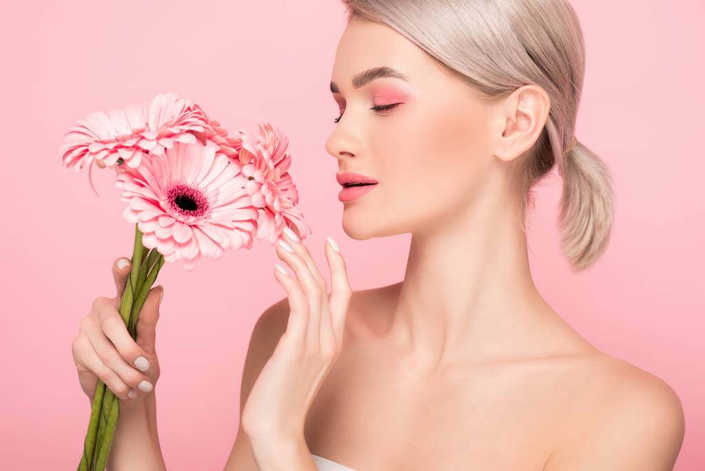 ελκυστική τρυφερή κοπέλα που κοιτάζει ροζ λουλούδια, απομονωμένη σε ροζ - Φωτογραφία, εικόνα