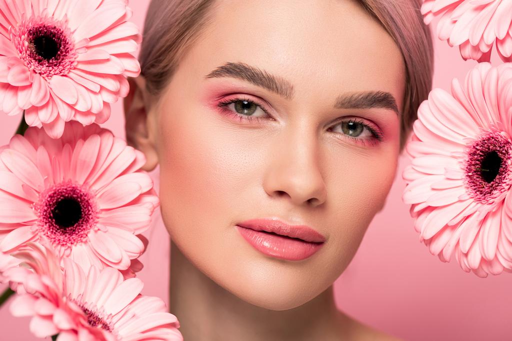 schönes Mädchen mit rosa Gerbera-Blüten, isoliert auf rosa - Foto, Bild