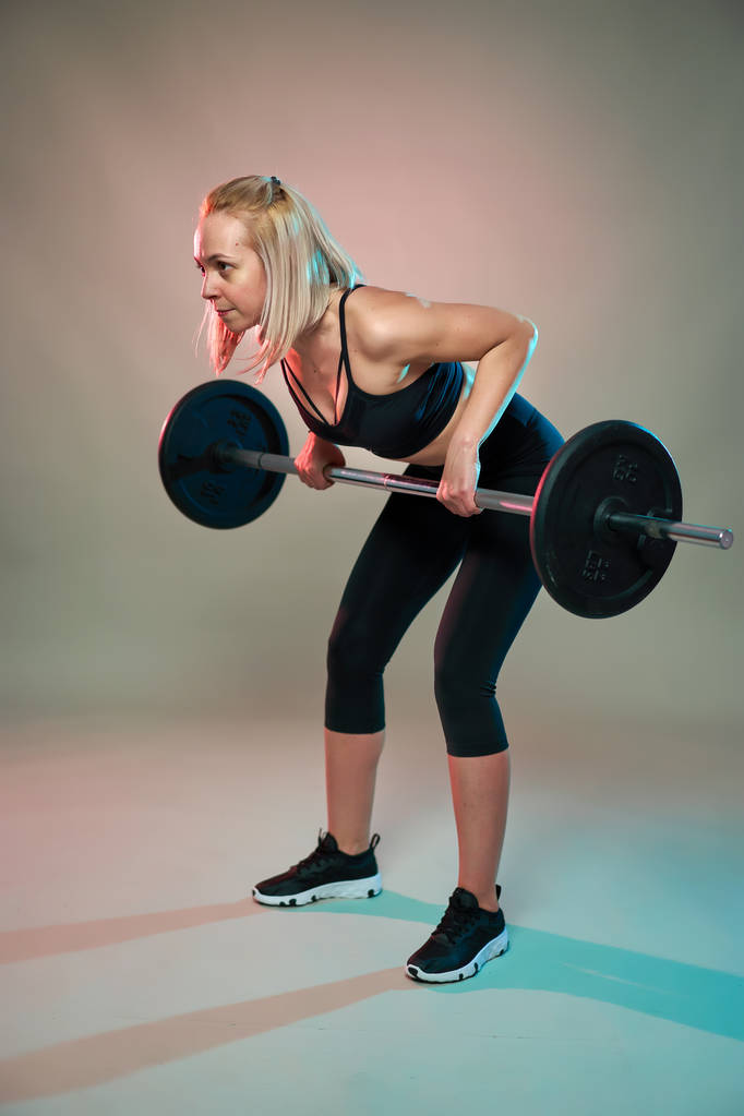 Chica de fitness haciendo filas con una barra pesada para el entrenamiento de espalda
 - Foto, Imagen