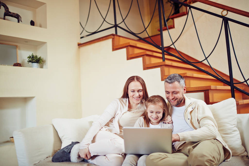 Szczęśliwa rodzina siedzi w domu i spędza wieczór z laptopem - Zdjęcie, obraz