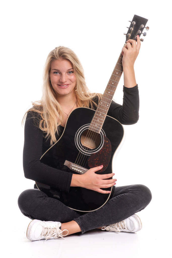 όμορφη ξανθιά κοπέλα κάθεται στη θέση του ράφτη και παίζει κιθάρα - Φωτογραφία, εικόνα