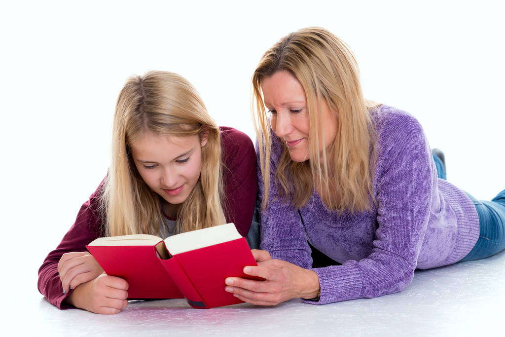 金髪の女の子と母親が床に横になって本を読んで - 写真・画像