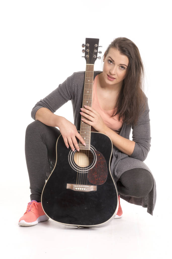 Nuori nainen kitara istuu lattialla
 - Valokuva, kuva