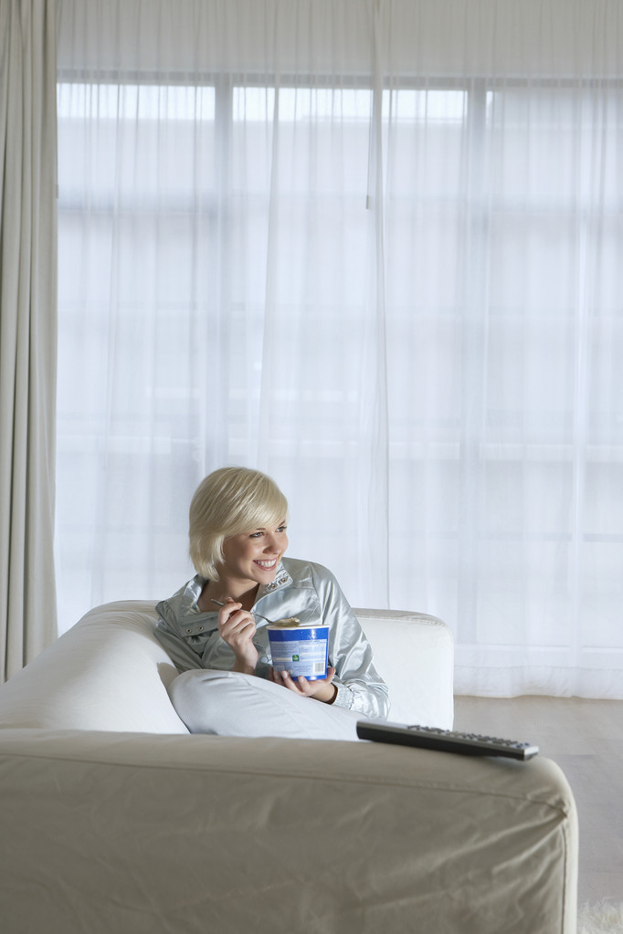 Mujer viendo televisión y comiendo helado
 - Foto, Imagen
