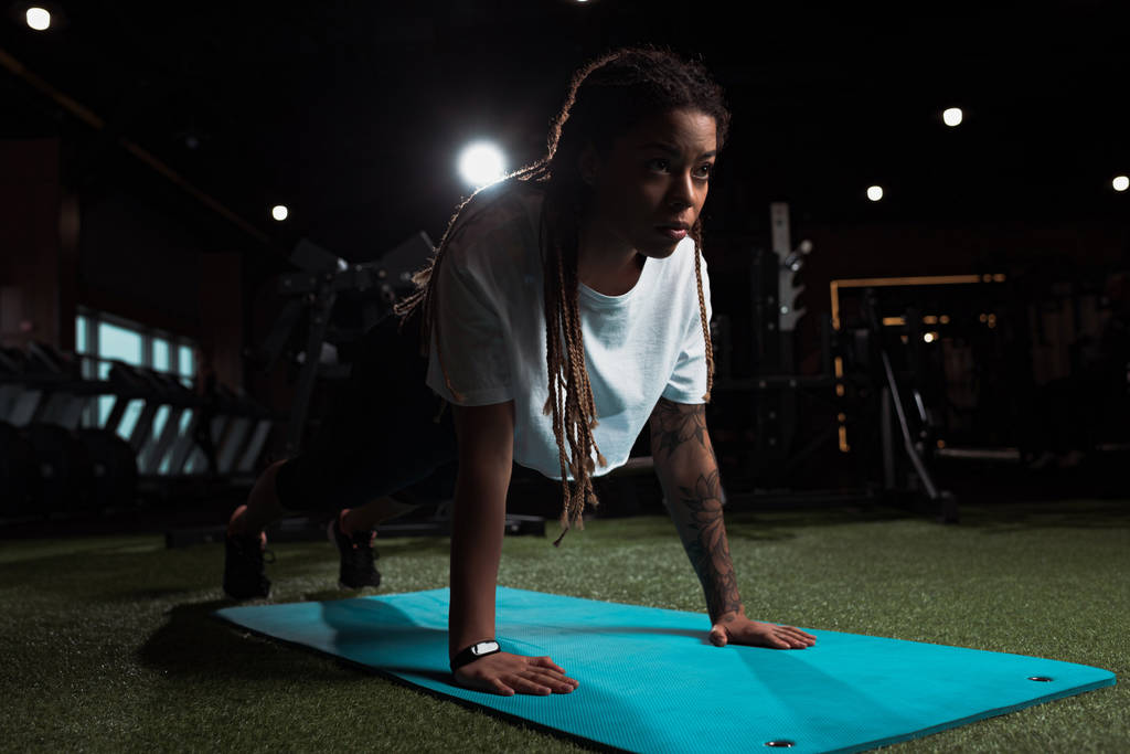 belle femme afro-américaine debout dans la planche sur tapis de fitness dans la salle de gym
 - Photo, image