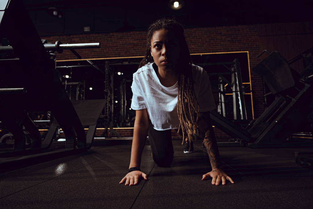 atractiva mujer afroamericana con rastas haciendo ejercicio de tablón en el gimnasio
  - Foto, Imagen