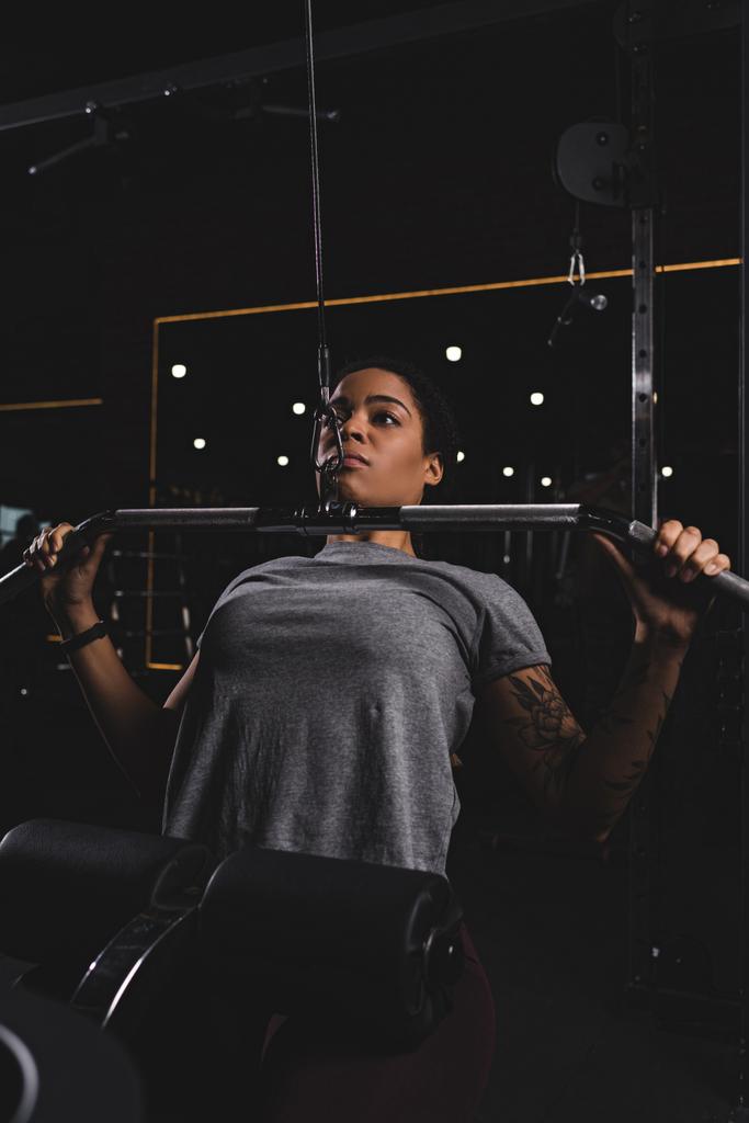 enfoque selectivo de chica afroamericana con entrenamiento de tatuaje en la máquina de gimnasio
 - Foto, Imagen