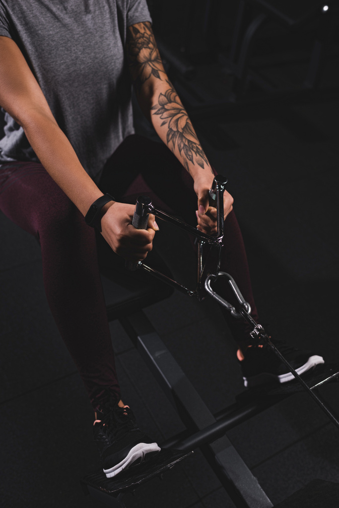 Ausgeschnittene Ansicht einer jungen afrikanisch-amerikanischen Sportlerin mit Tätowierung beim Turnen im Fitnessstudio  - Foto, Bild