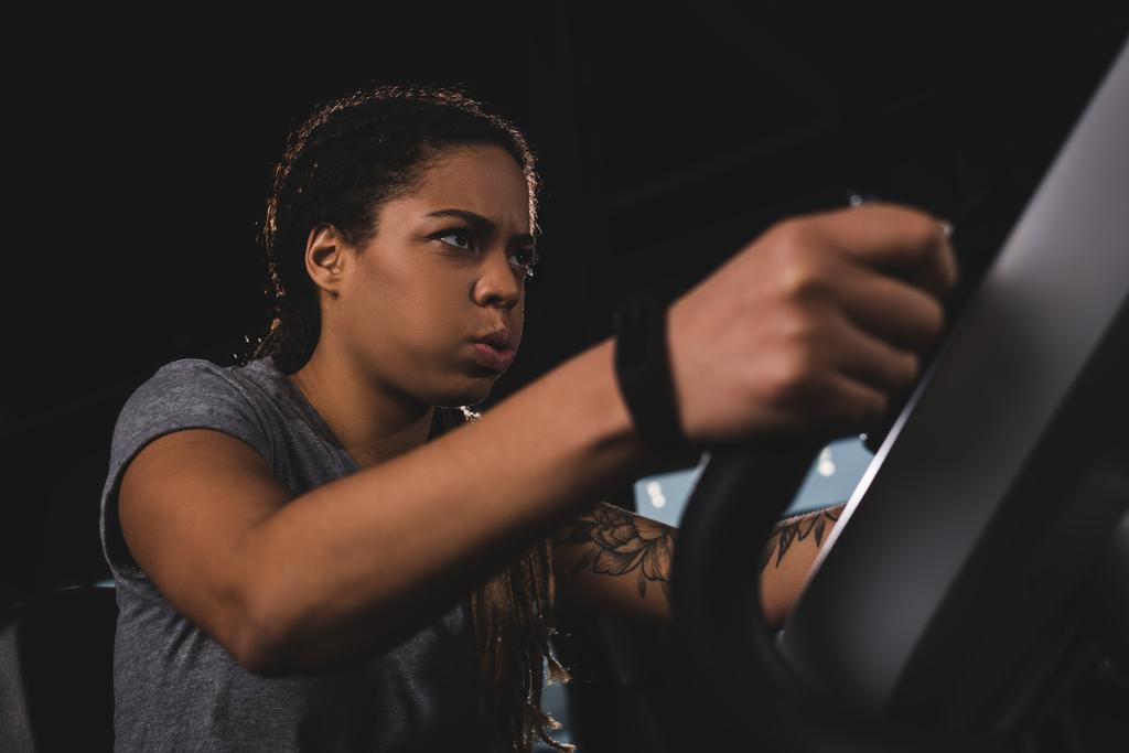 selective focus of focused african american girl with smartwatch training on gym machine  - Fotoğraf, Görsel
