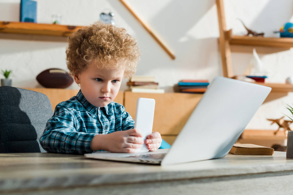 szelektív fókusz okos gyermek gazdaság okostelefon laptop közelében  - Fotó, kép