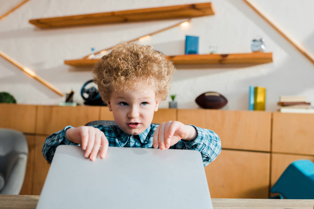 adorable e inteligente niño tocando portátil mientras estudia en casa
 - Foto, Imagen